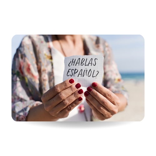 Closeup of a caucasian woman outdoors showing a piece of paper with the question hablas español.
